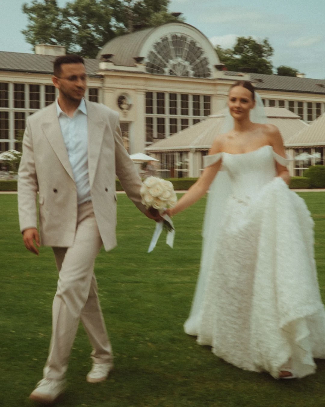 Para młoda trzymająca się za ręce przed elegancką rezydencją